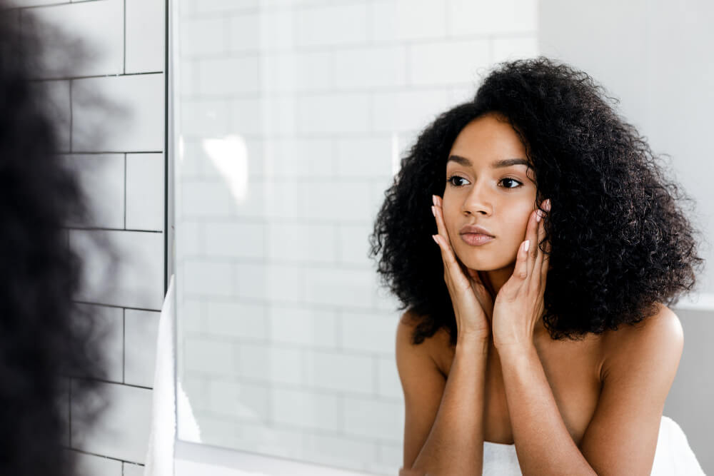 Woman looking in mirror at winter skin problems