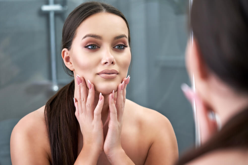 Woman looking at skin in mirror