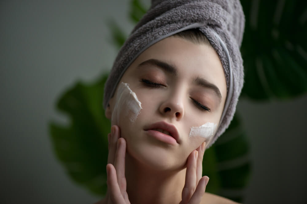 Woman applying creams from grapes to face