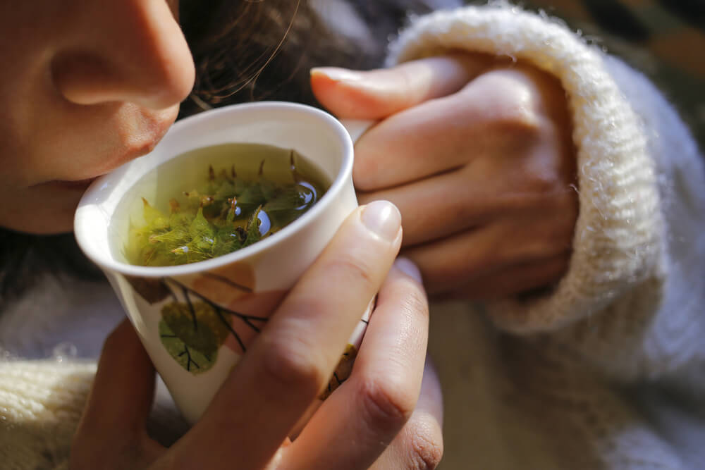 Woman drinking herbal tea to de-stress for your skin