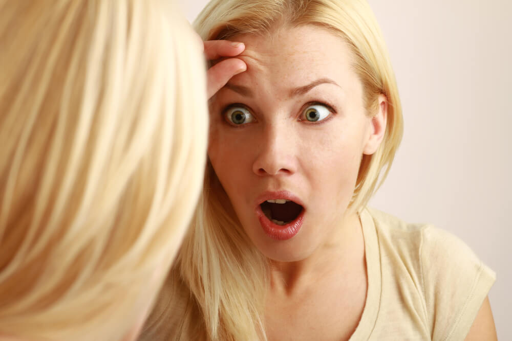 Woman looking at skin in mirror