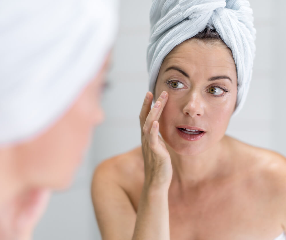 Woman looking at skin in mirror