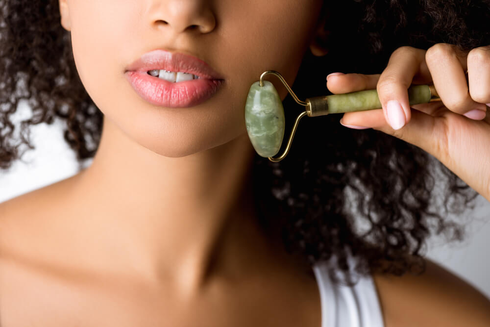 Woman using jade roller on face