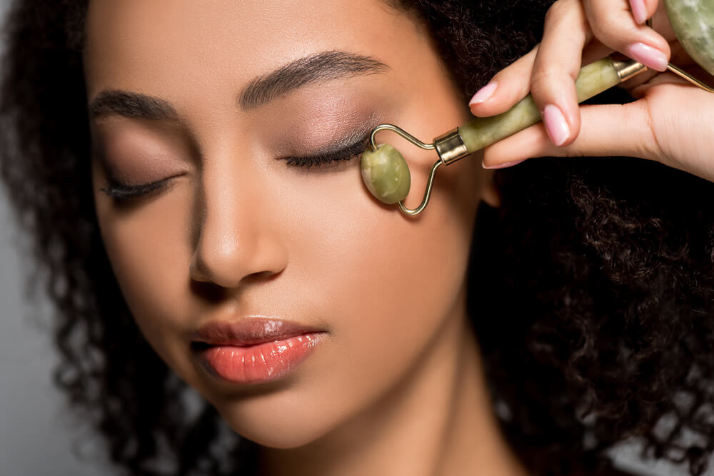 Woman using jade roller on face