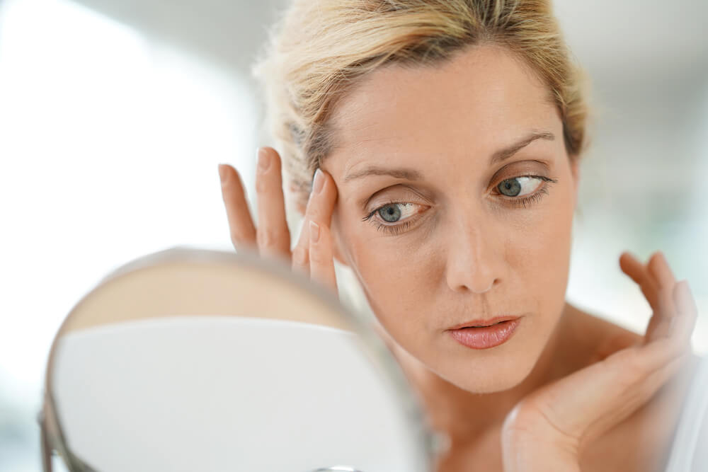 Woman looking at skin in mirror