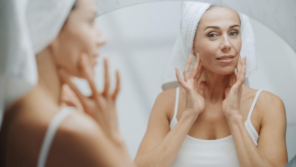 Woman looking at skin in mirror after using facial peel