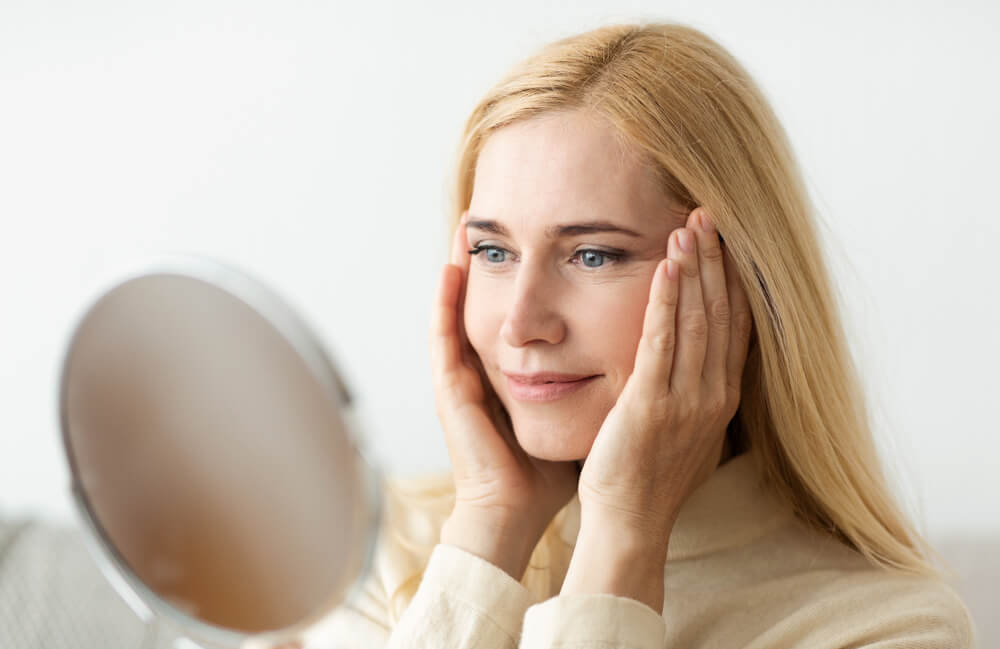 Woman looking at skin in mirror