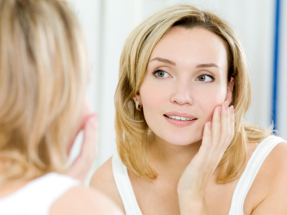 Woman looking at skin in mirror