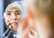 Woman looking at aging skin signs in mirror