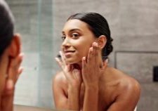 Woman looking at skin in mirror